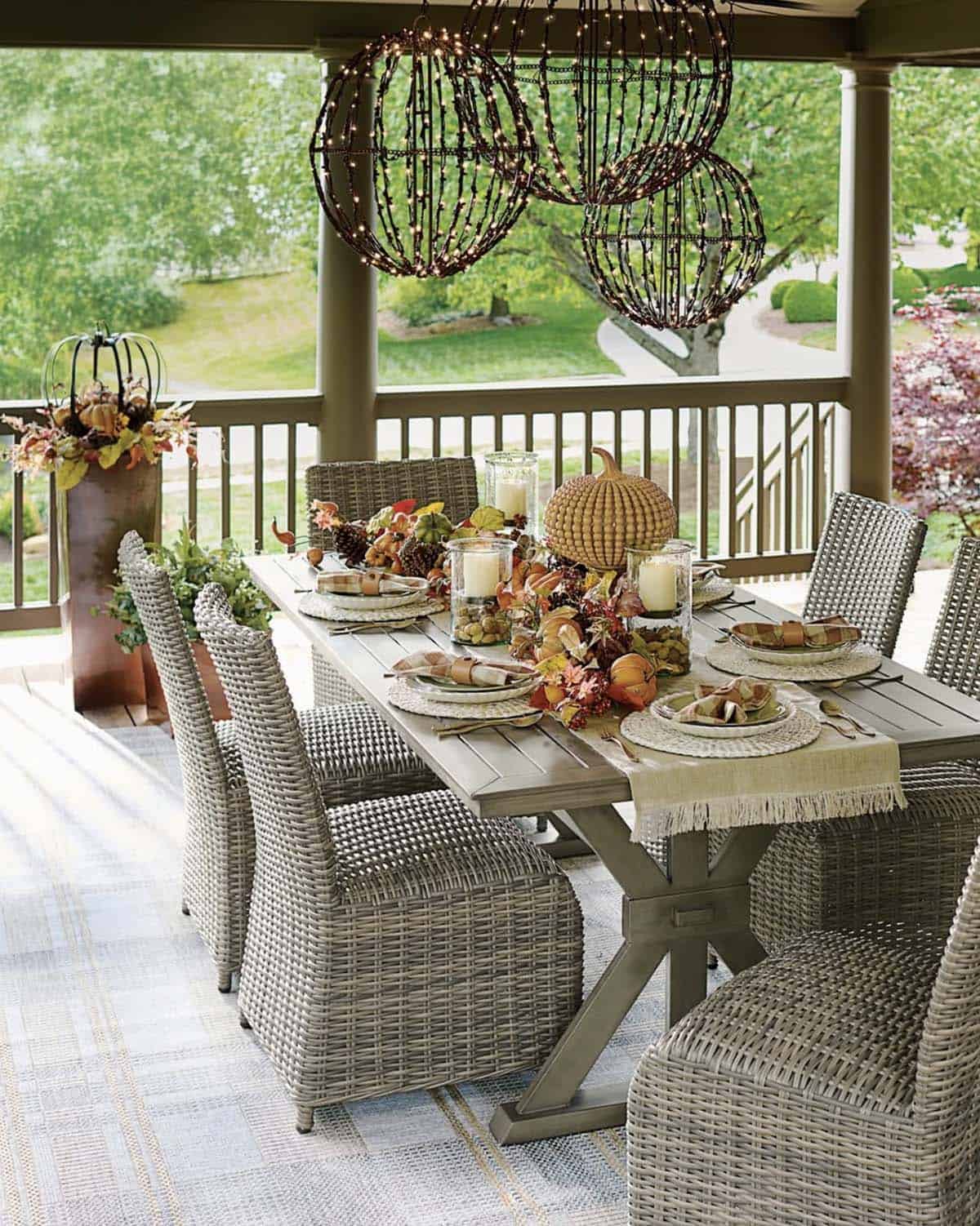 Lit wire sphere chandeliers hanging over an outdoor fall table setting