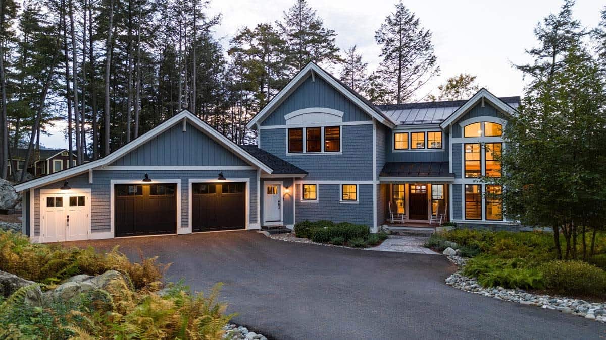 Front exterior at dusk with dark garage doors and gray shingle siding