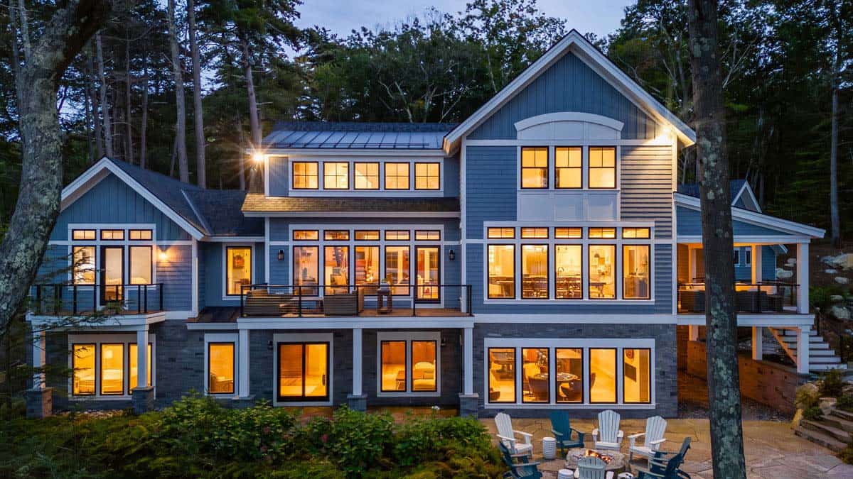 Lakeside facade with decks, stone base, and Adirondack chairs around fire pit