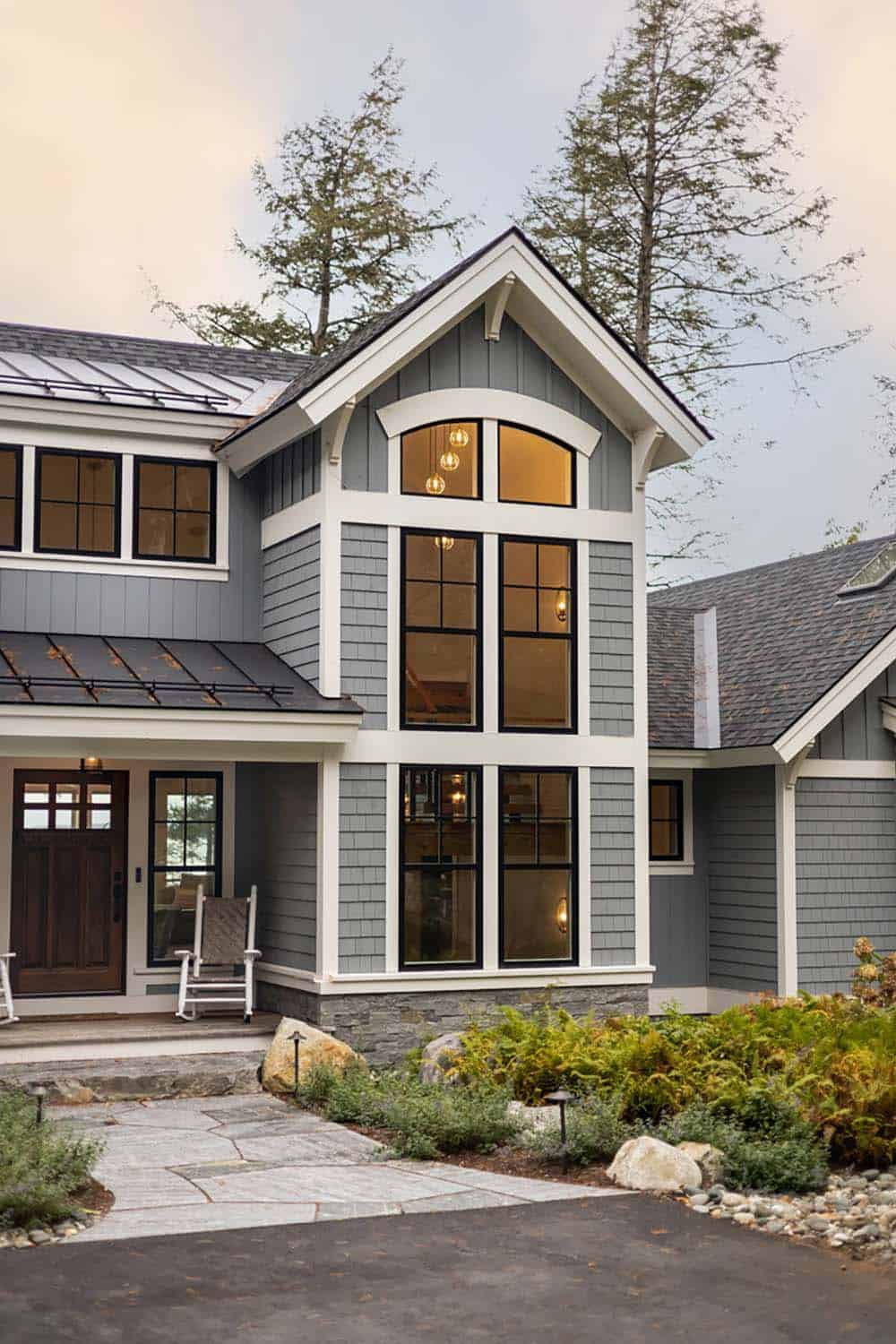 Front entry with tall arched windows, wood door, and stone-clad base