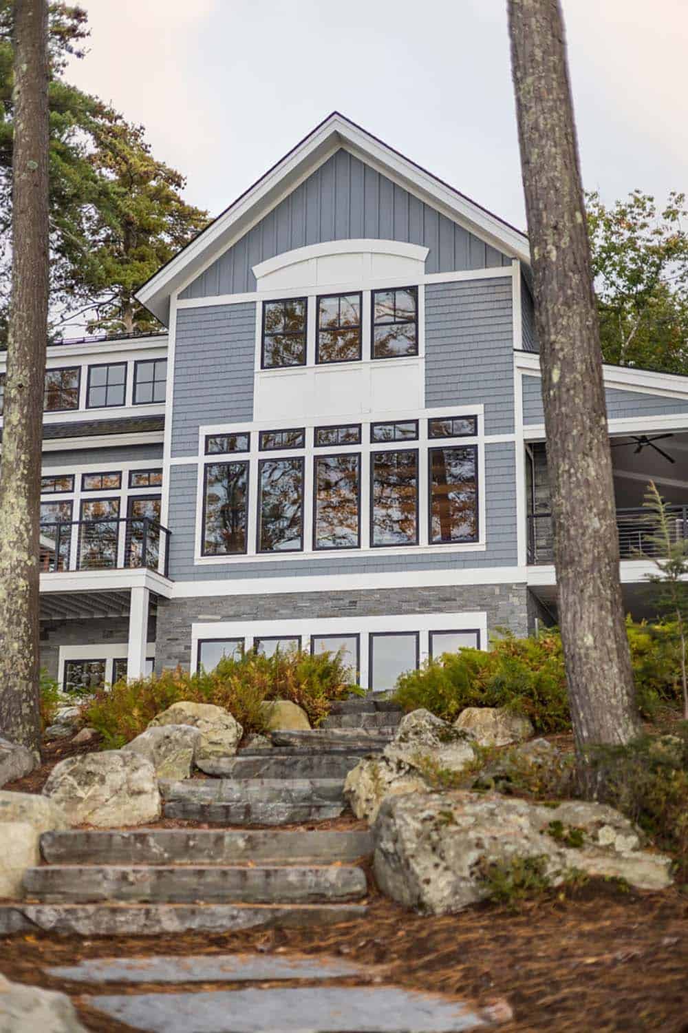 Stone steps climb toward cottage gable with white trim and black windows