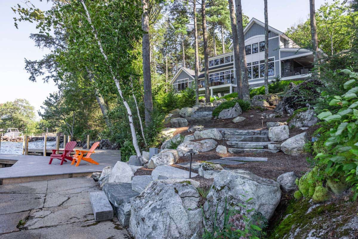 Red and orange Adirondack chairs on dock below landscaped stone steps