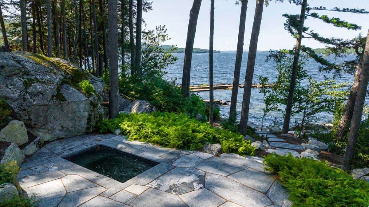Flagstone patio with sunken spa overlooking Lake Winnipesaukee through tall pines