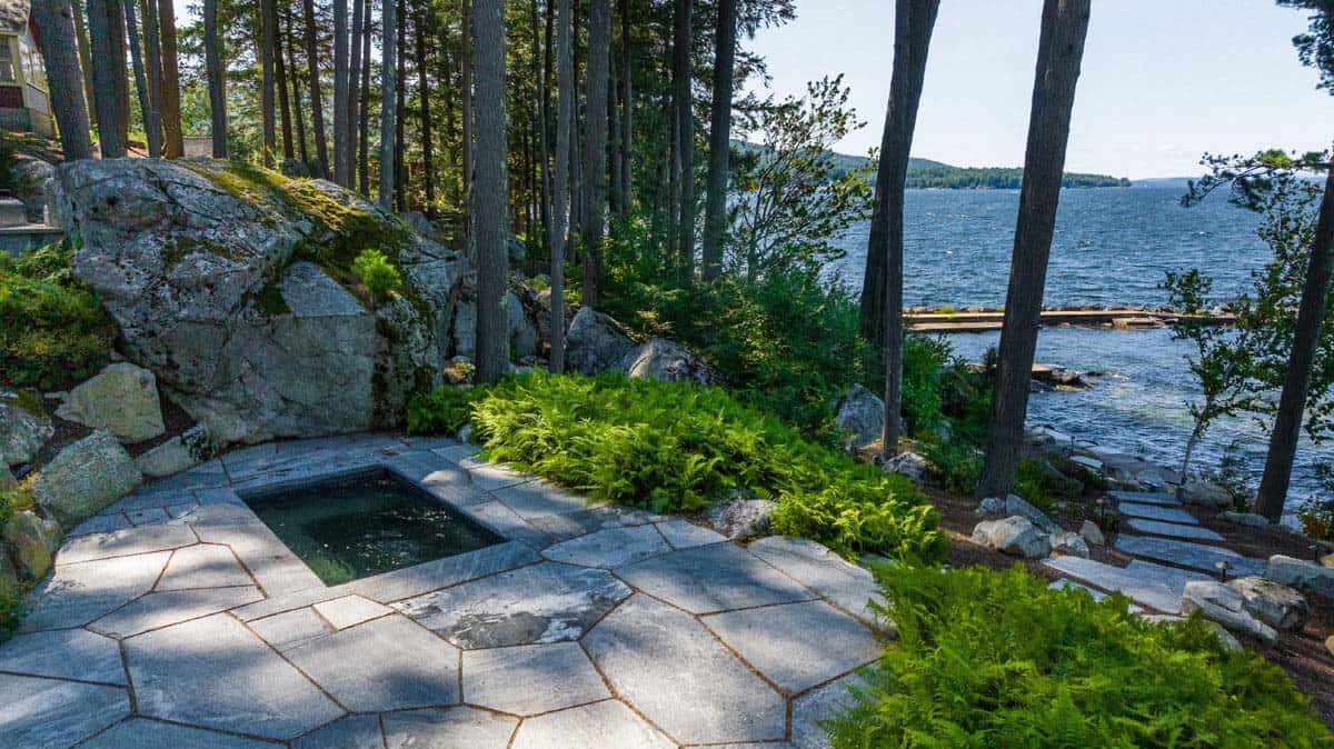 Sunken spa, fern beds, and stepping stone path leading toward the lake