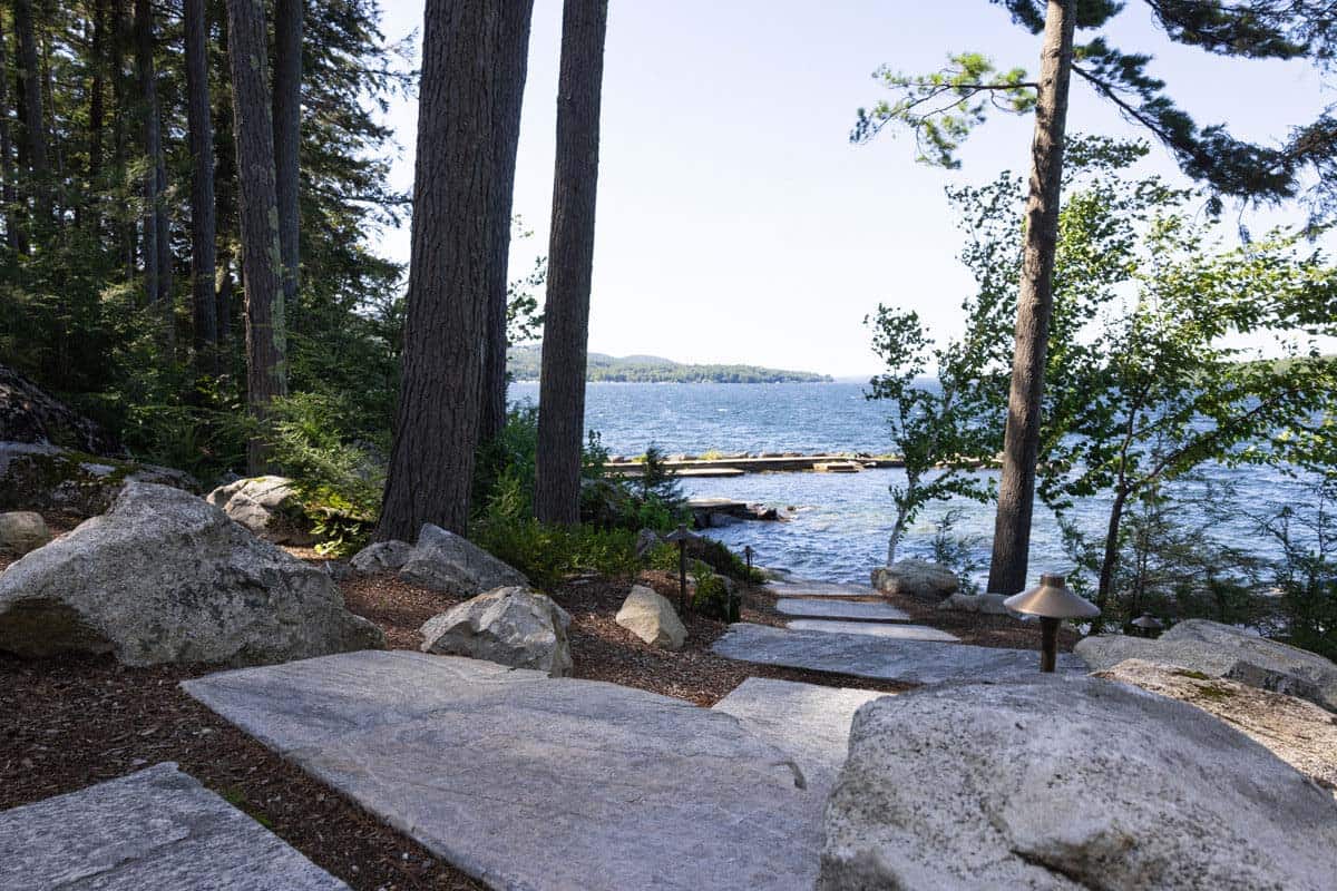 Stone stepping path with boulders and path lights leads toward the water