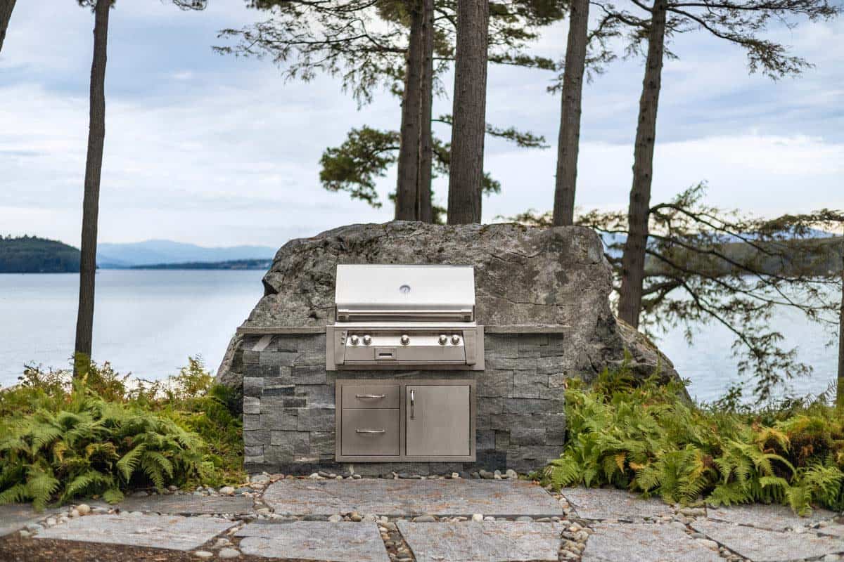 Built-in grill with stone base set into a boulder beside the lake