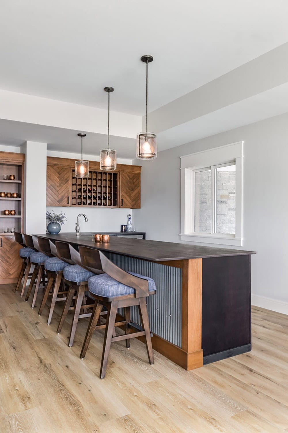 Wet bar with herringbone cabinetry, wine storage, and upholstered counter stools