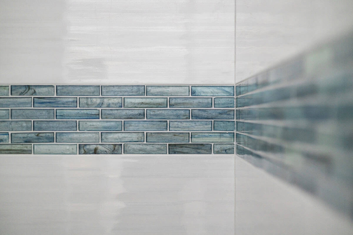 Close-up of blue glass tile accent band in white shower