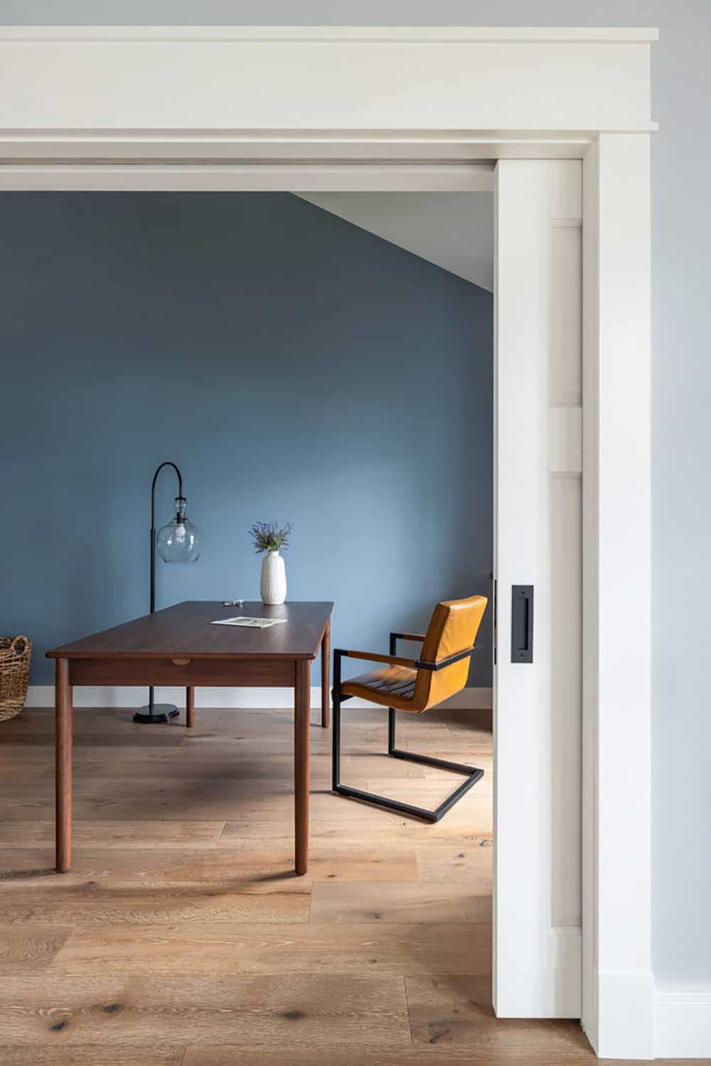 Office with walnut desk and blue walls seen through open pocket door