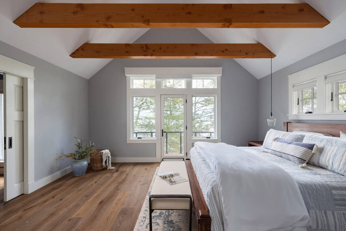 Primary bedroom with exposed beams, vaulted ceiling, and balcony door