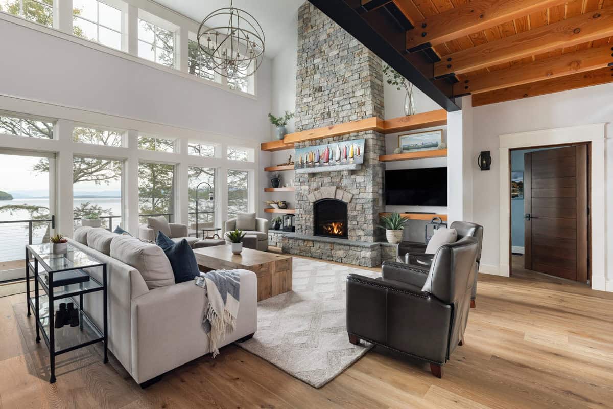 Great room with stone fireplace, timber beams, and lake views