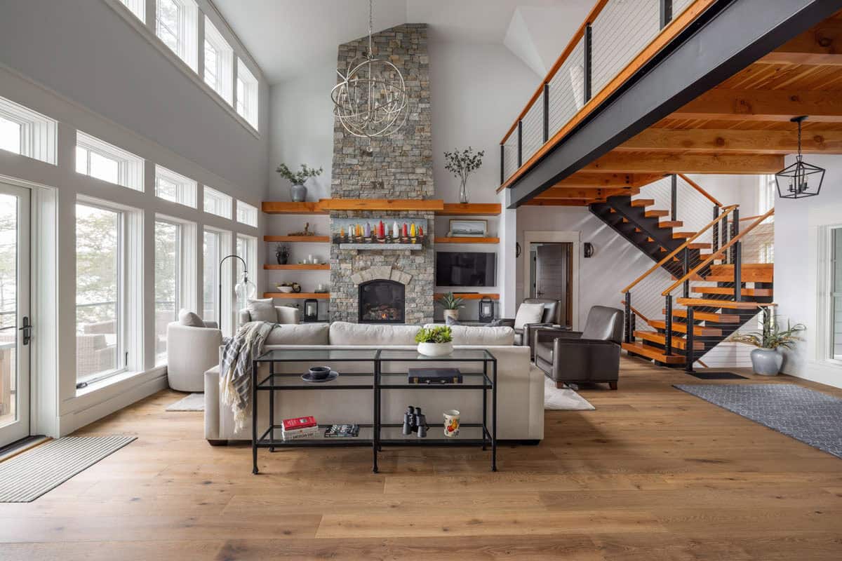 Living room with two-story stone fireplace, open staircase, and loft overlook