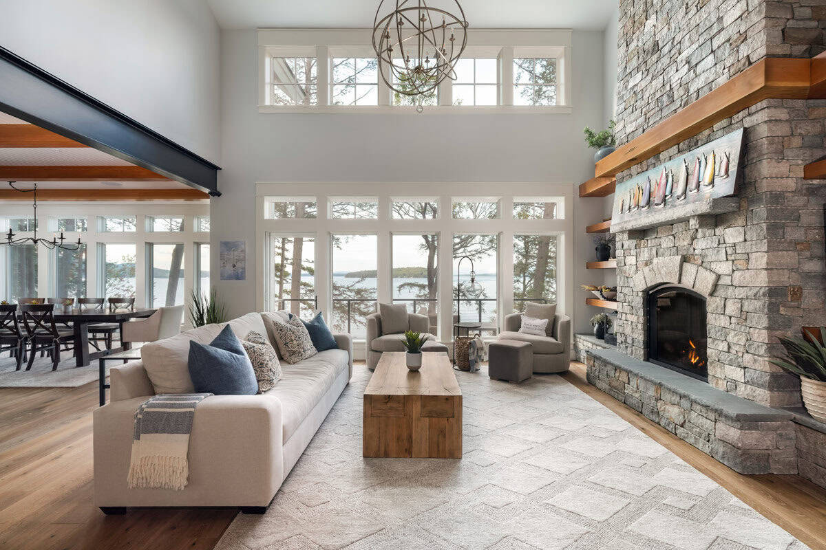 Living room with sofa, swivel chairs, and tall windows facing the lake
