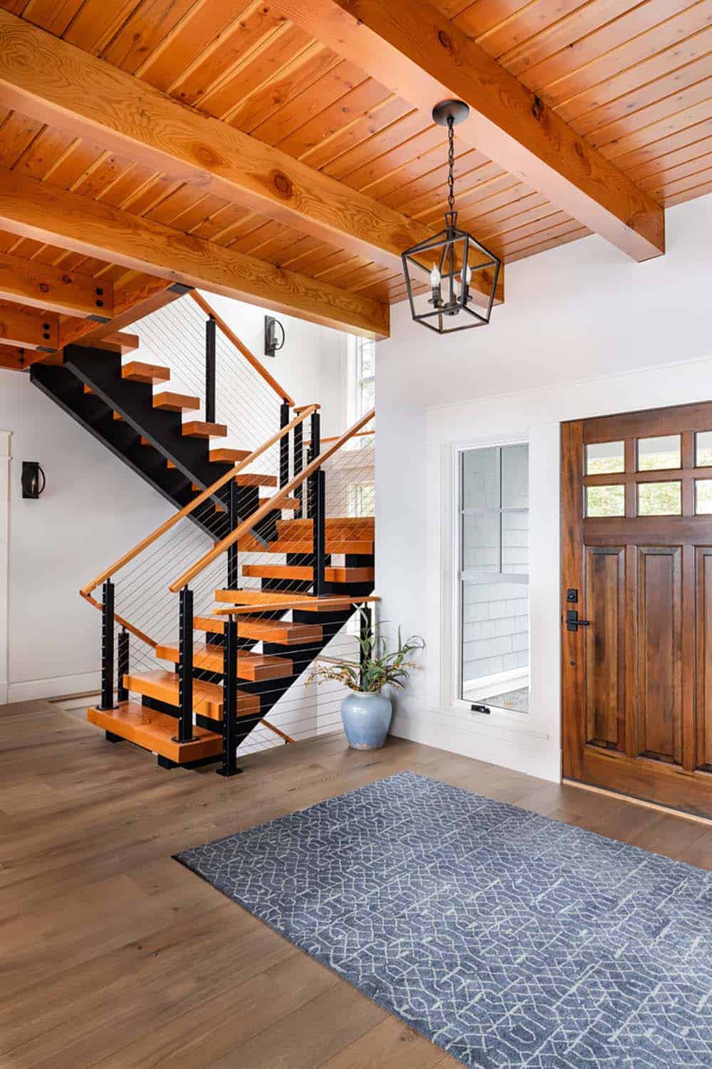 Entry with wood front door, lantern pendant, and open staircase