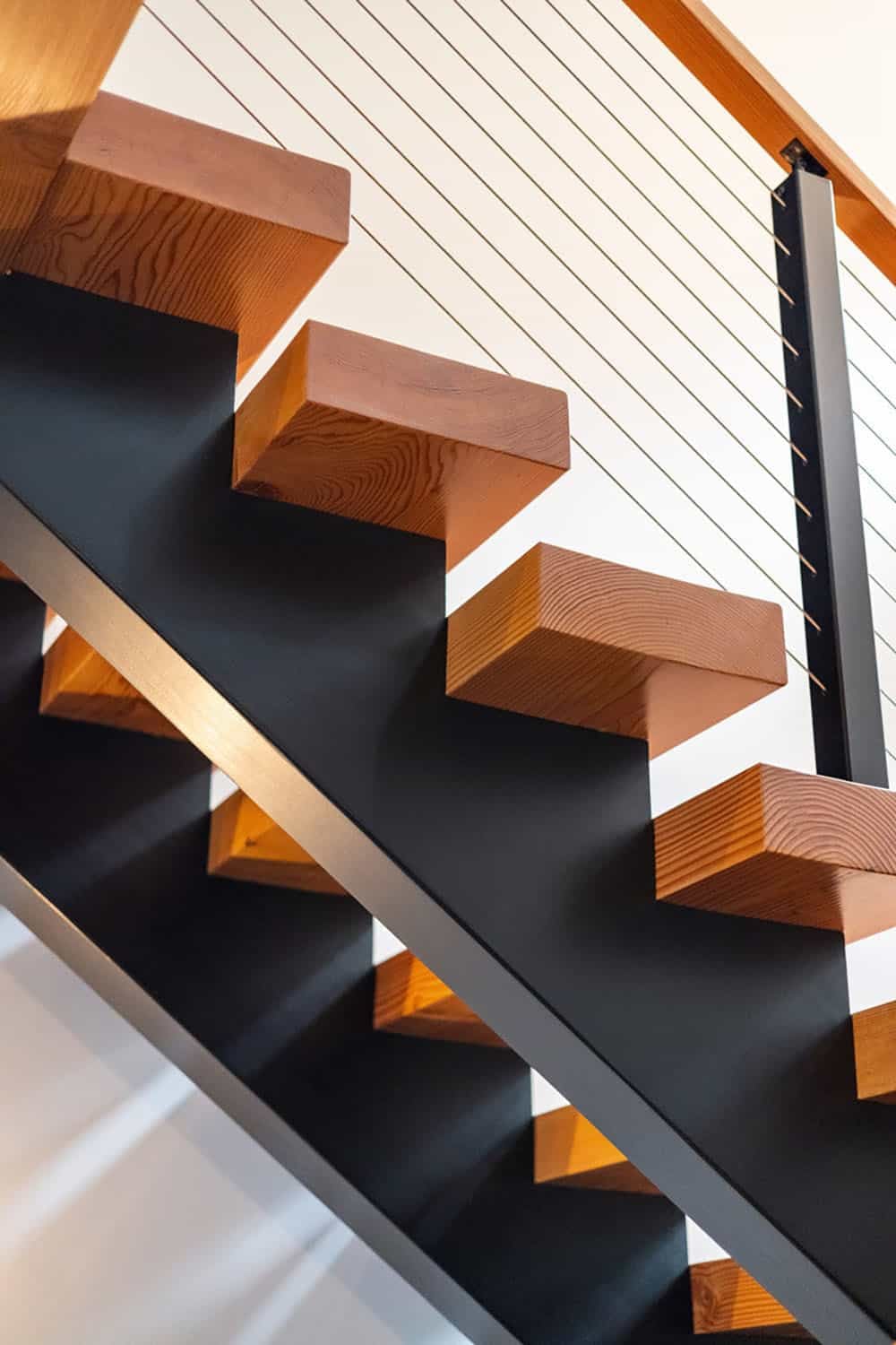 Wood stair treads on black steel stringer with cable railing