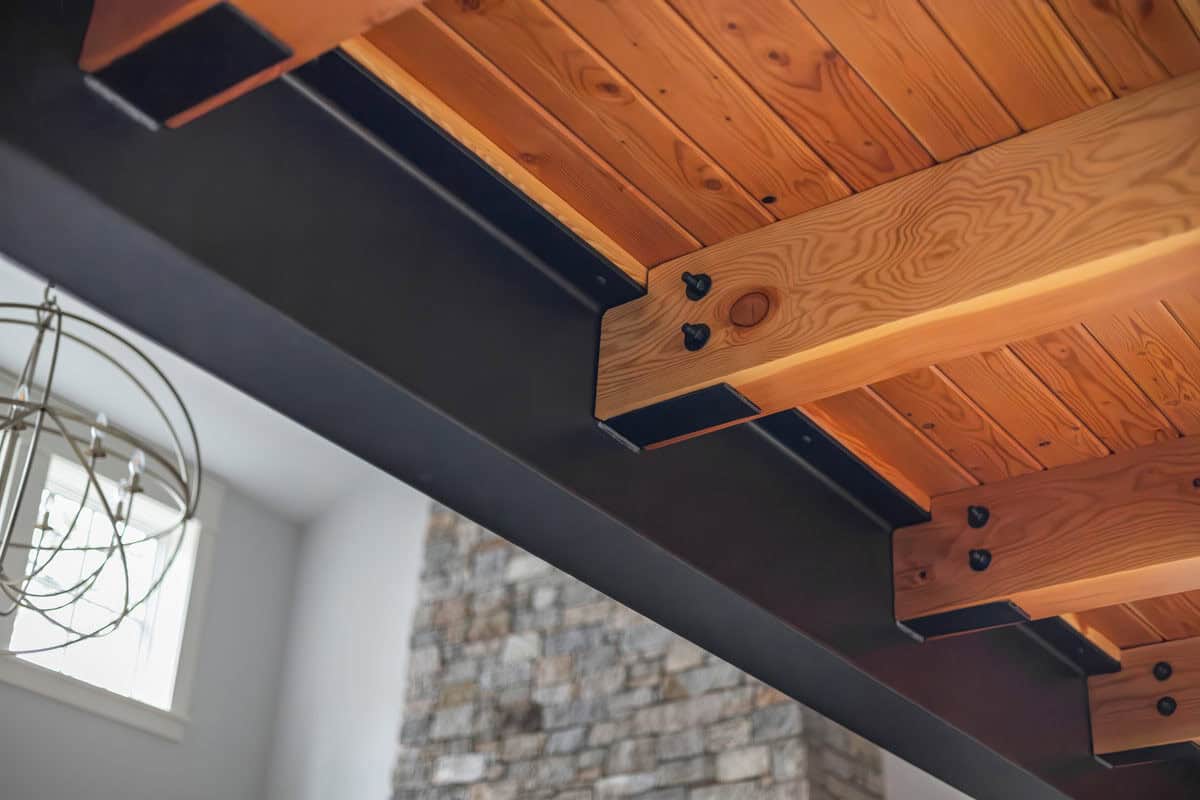 Bolted timber joists and steel beam beneath wood plank ceiling