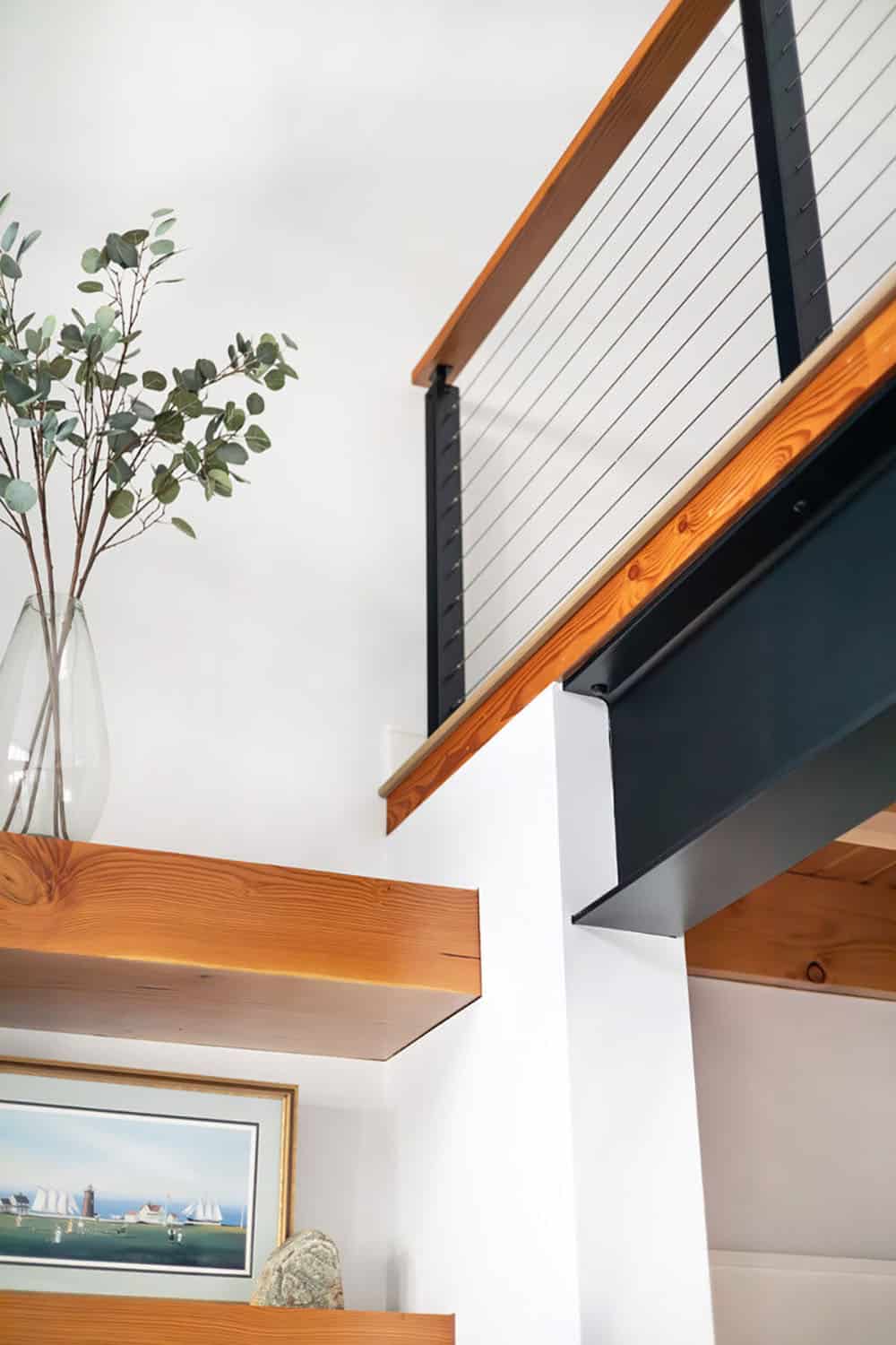Loft cable railing with steel beam above floating wood shelves