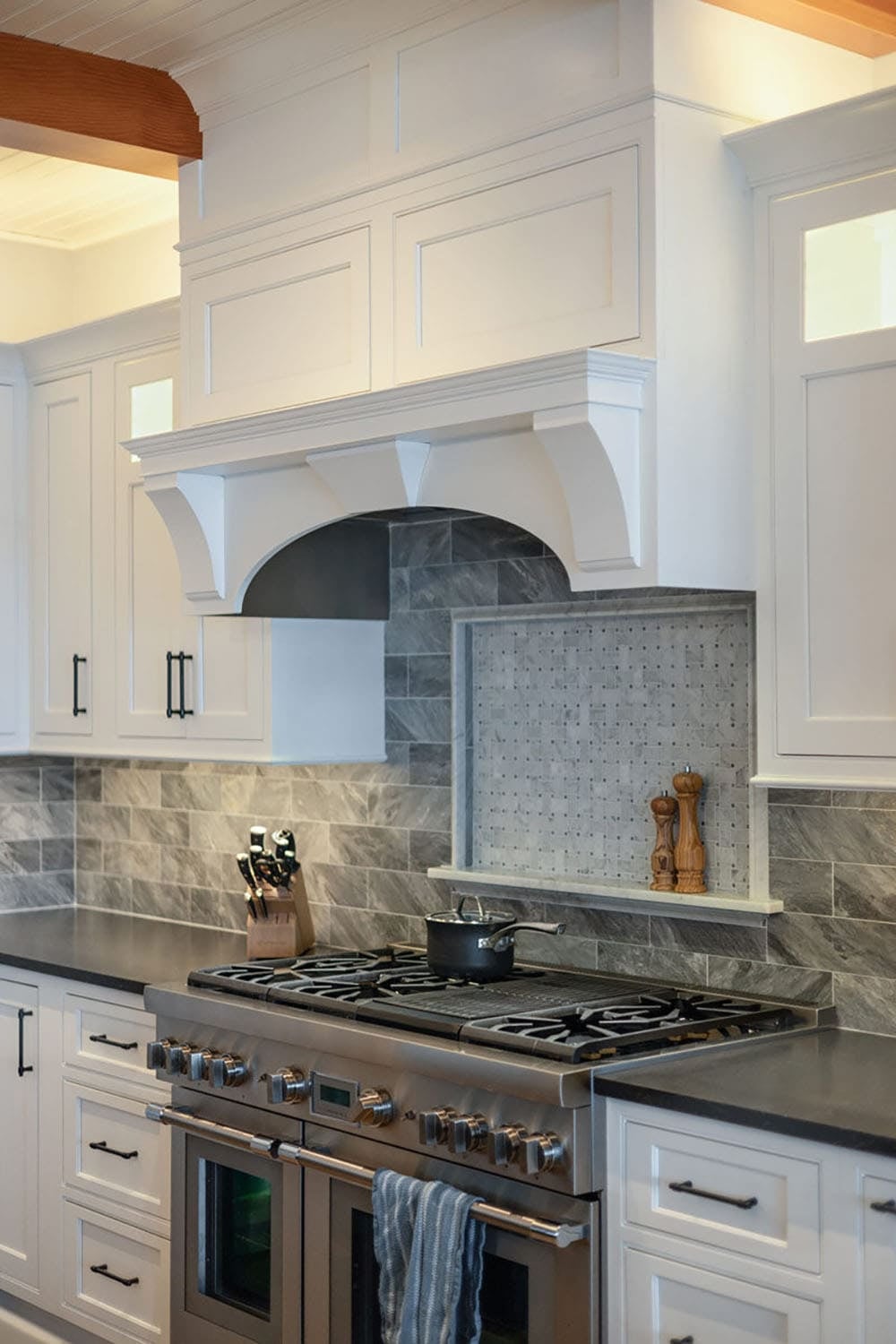 Range with custom white hood and gray tile backsplash with mosaic inset