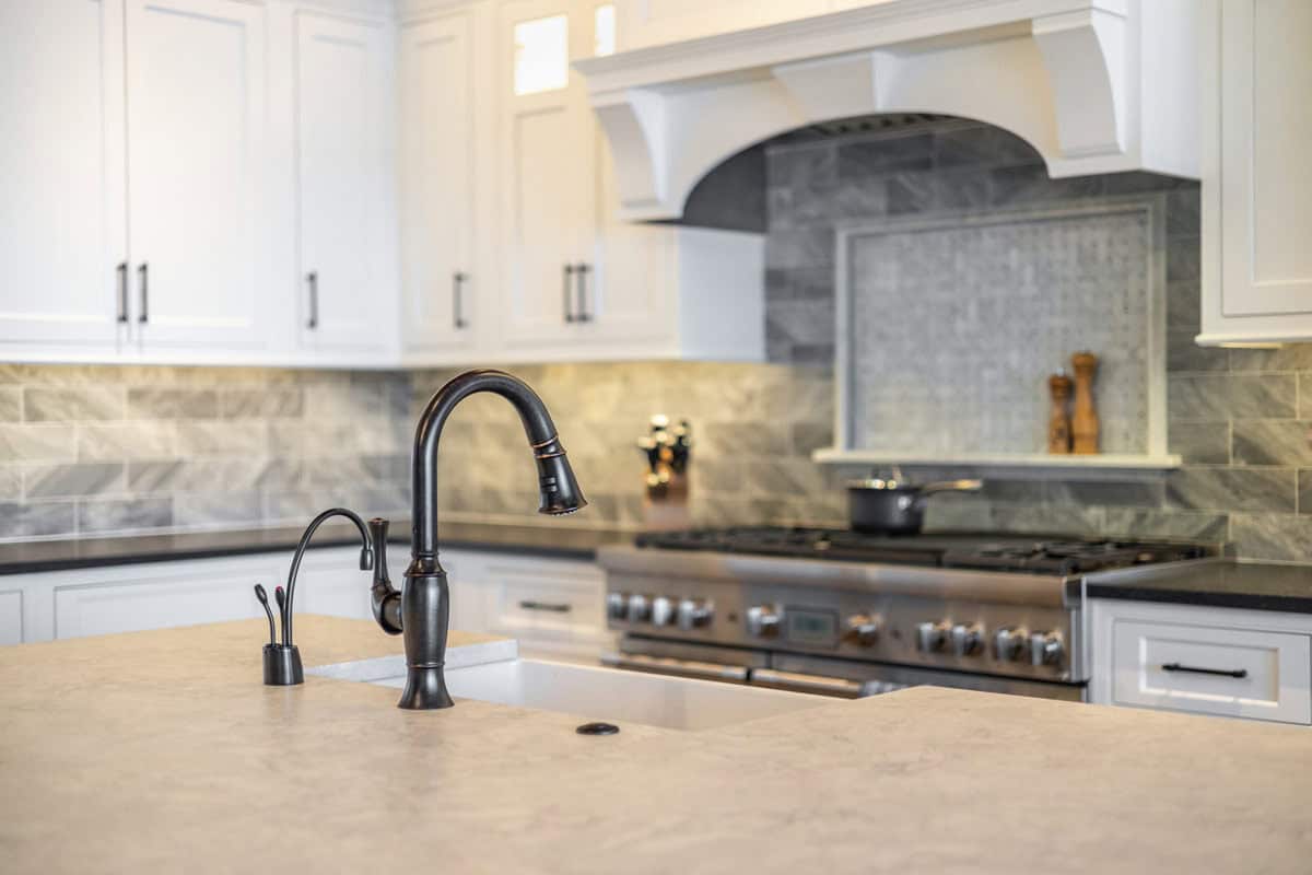 Island sink with oil-rubbed bronze faucet and range in background