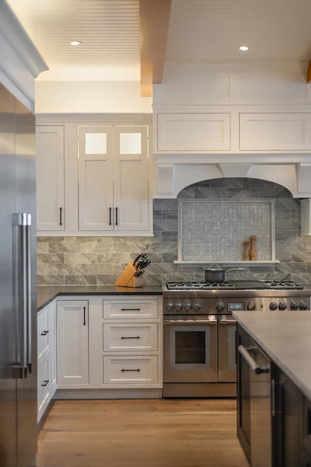 Kitchen range with white hood, mosaic backsplash inset, and refrigerator at left