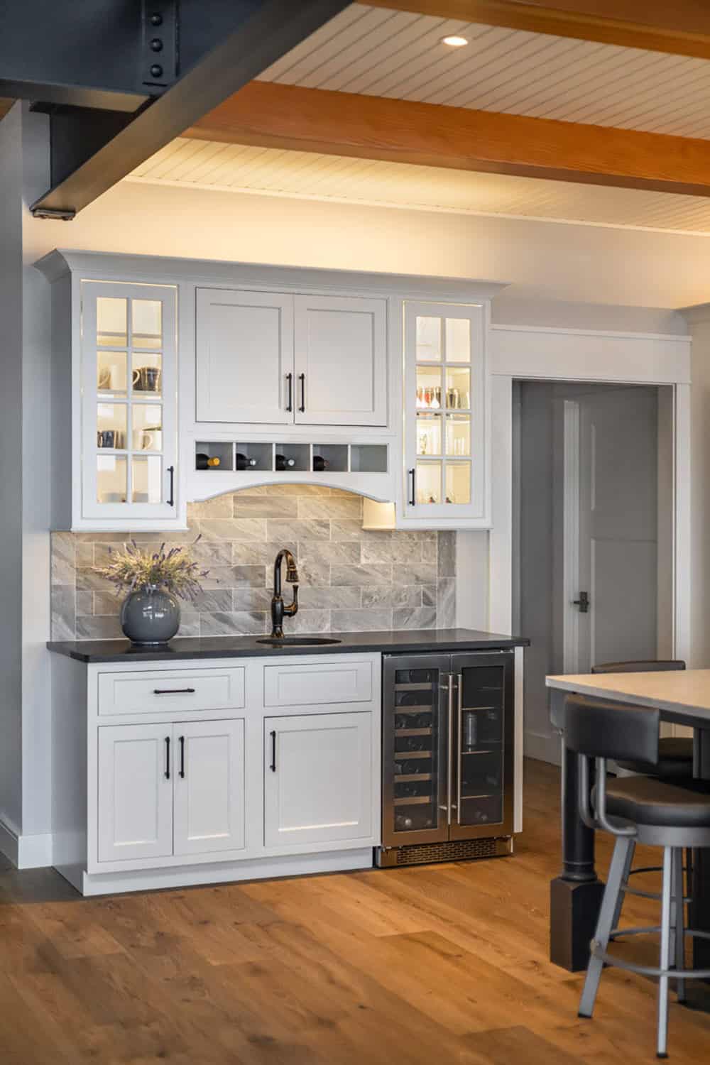 Kitchen bar with glass-front cabinets, wine rack, and dual-zone wine refrigerator