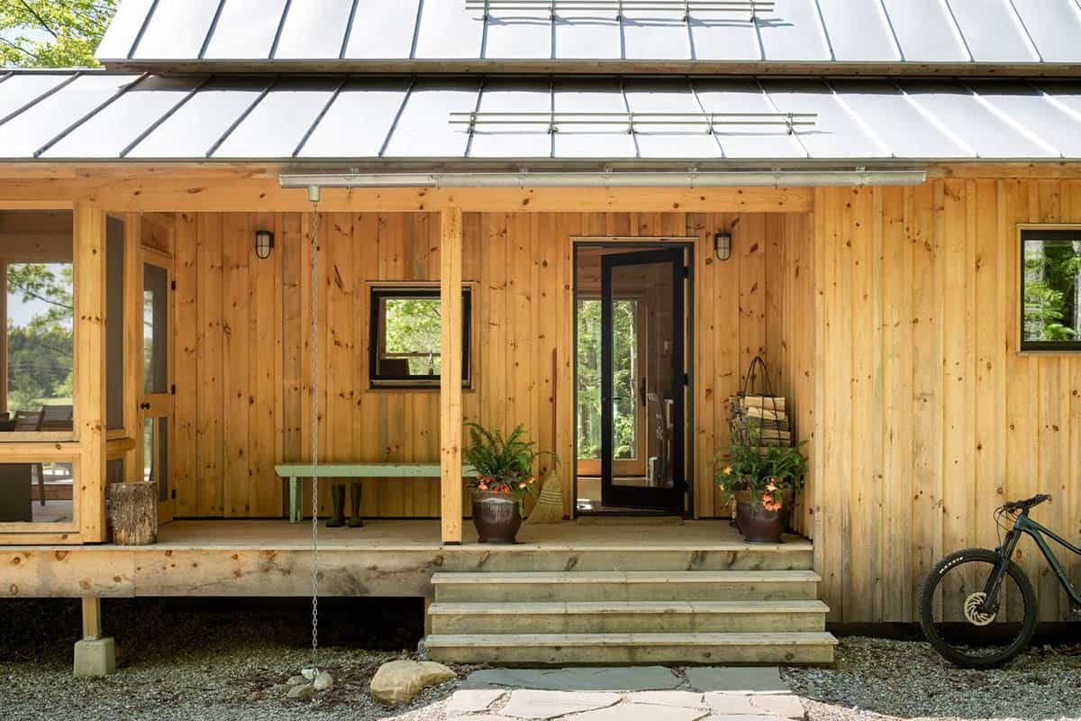 Covered front porch with green bench, wood steps, and stone path