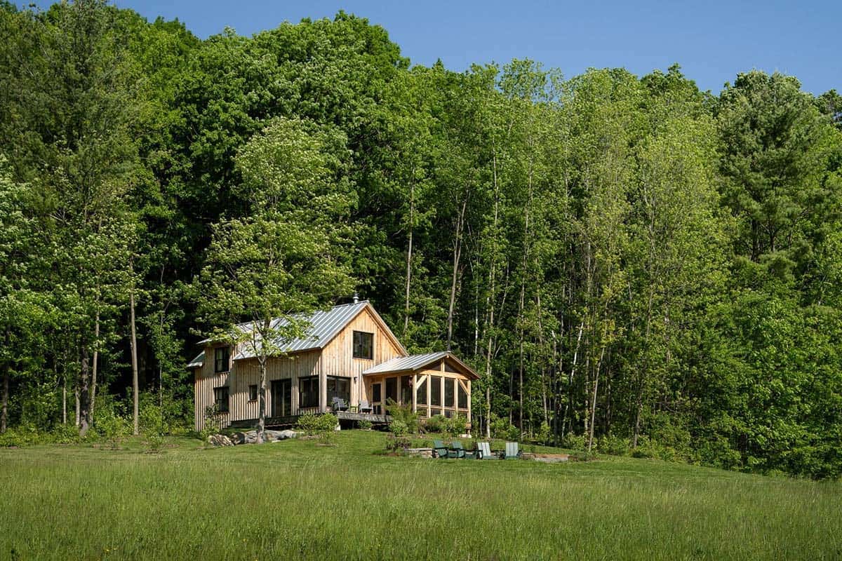 Vermont cabin tucked into the tree line above a meadow