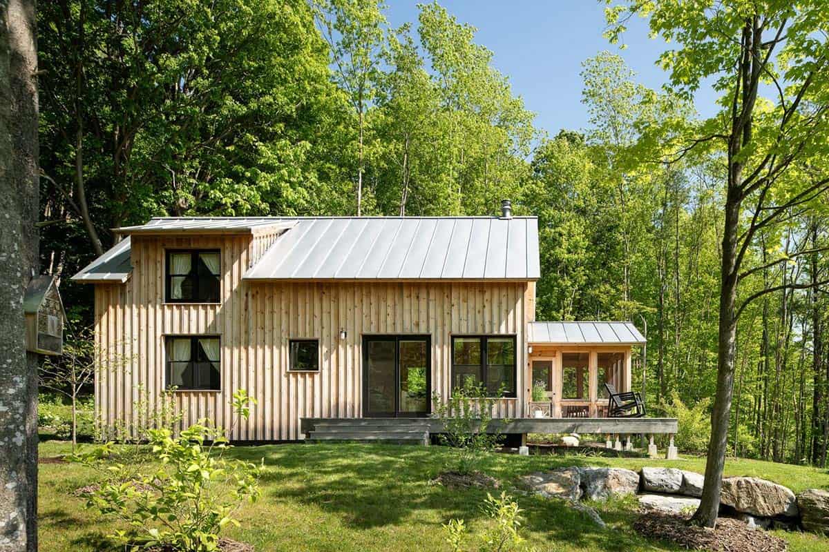 Rear cabin facade with black windows, deck, and screened porch