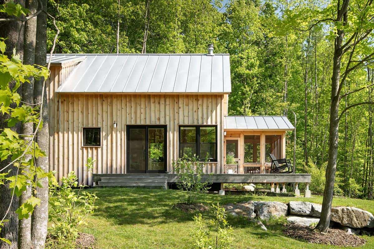 Wood cabin deck and screened porch surrounded by trees and boulders