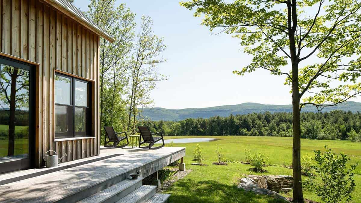 Deck rocking chairs overlooking a meadow, pond, and distant mountains
