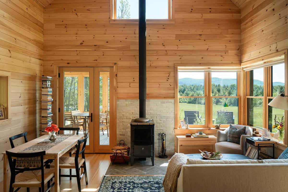 Wood-paneled living room with wood stove, dining table, and mountain views