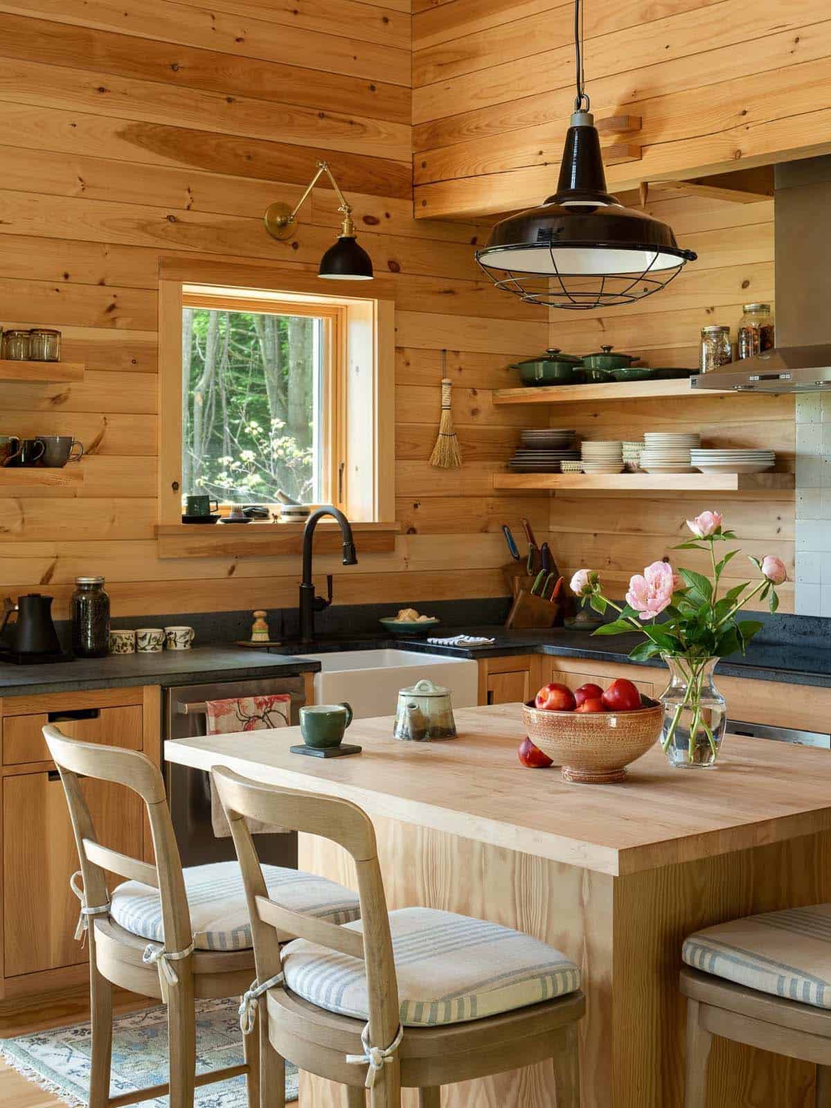 Kitchen island with cushioned stools, black pendant light, and open shelves