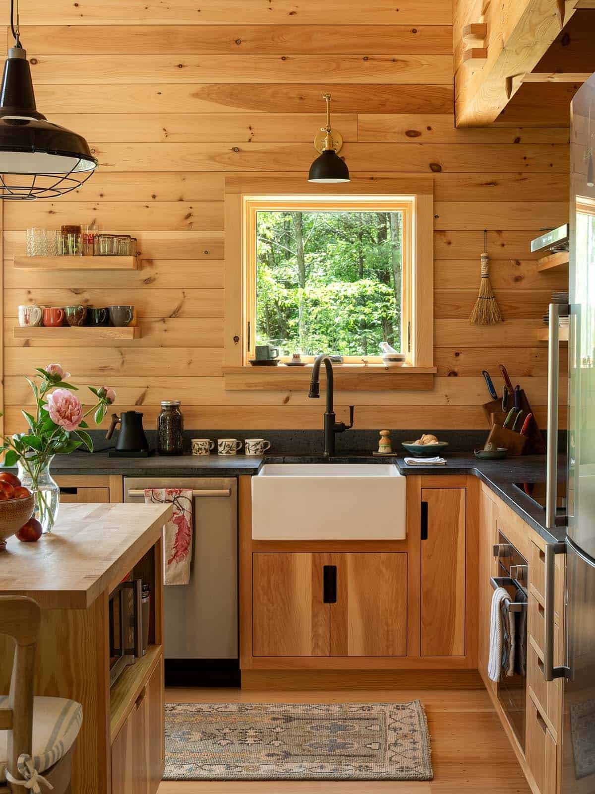 Farmhouse sink under window with black faucet and dark countertops