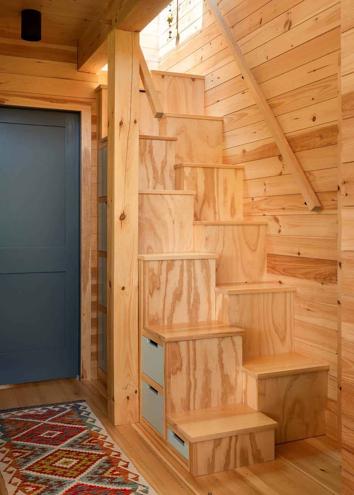 Plywood storage stairs with built-in drawers beside a blue door