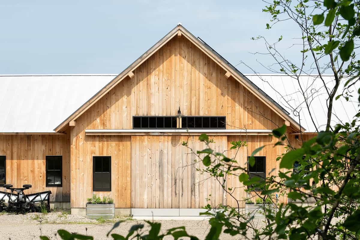 Barn gable end with sliding wood door, high windows, and metal planters