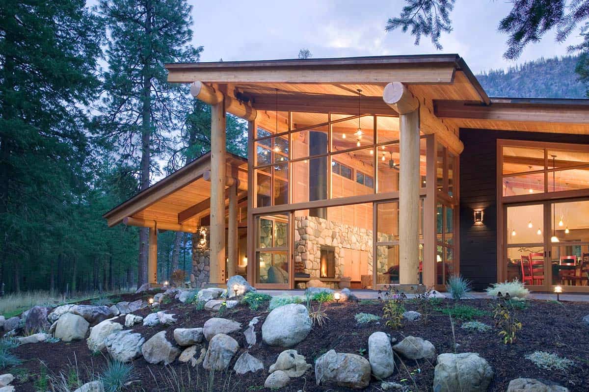Cabin exterior at dusk with glowing windows and stacked stone landscaping