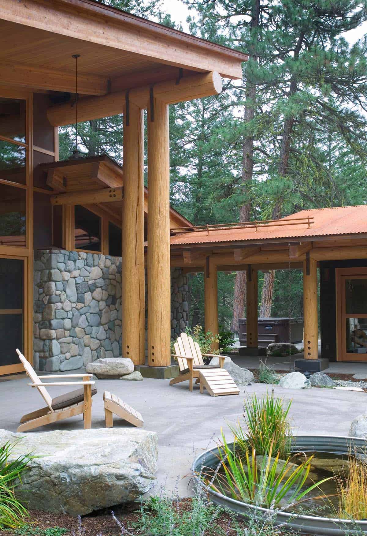 Covered breezeway with stone columns, Adirondack chairs, and stock tank pond