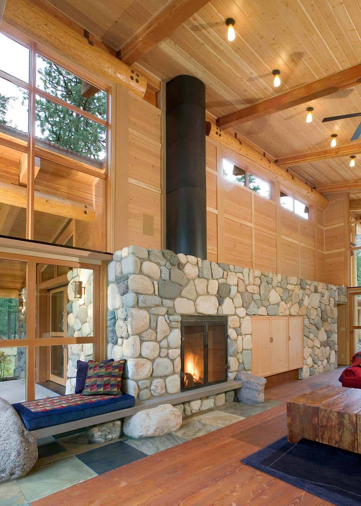Stone fireplace with black flue and built-in cabinetry
