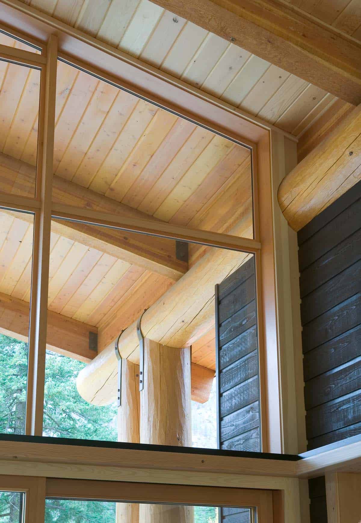 Detail of log beam connection against dark wood siding exterior