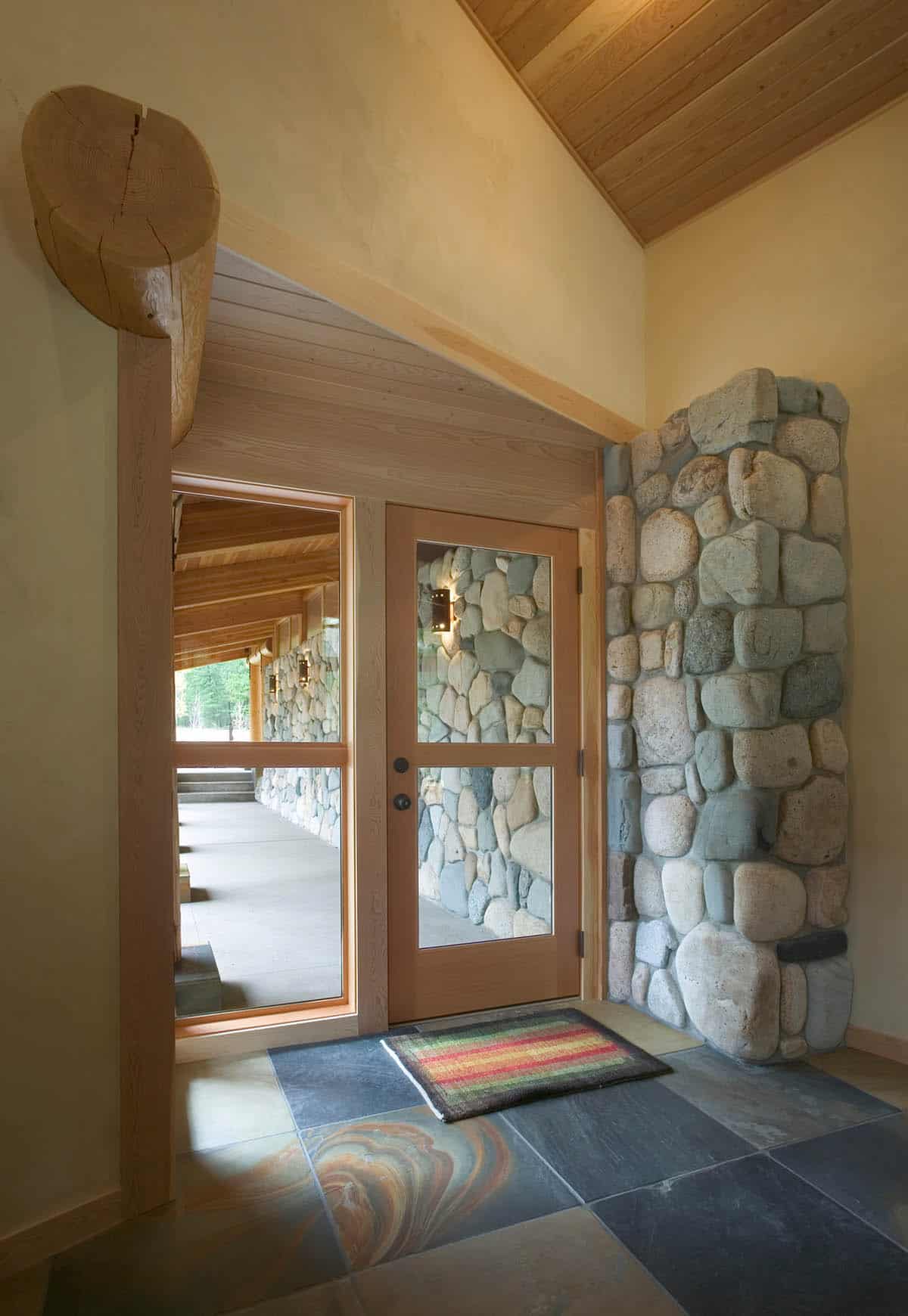 Entryway with stone wall, glass door, and vaulted wood ceiling