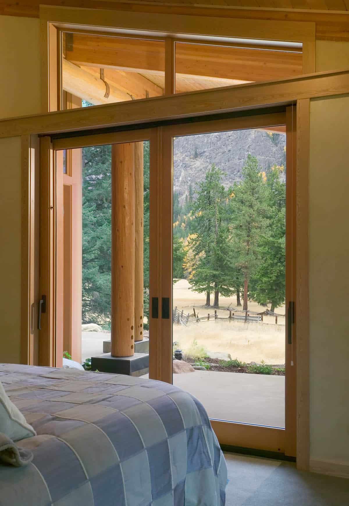 Bedroom sliding doors opening to patio, meadow, and cliffside pines