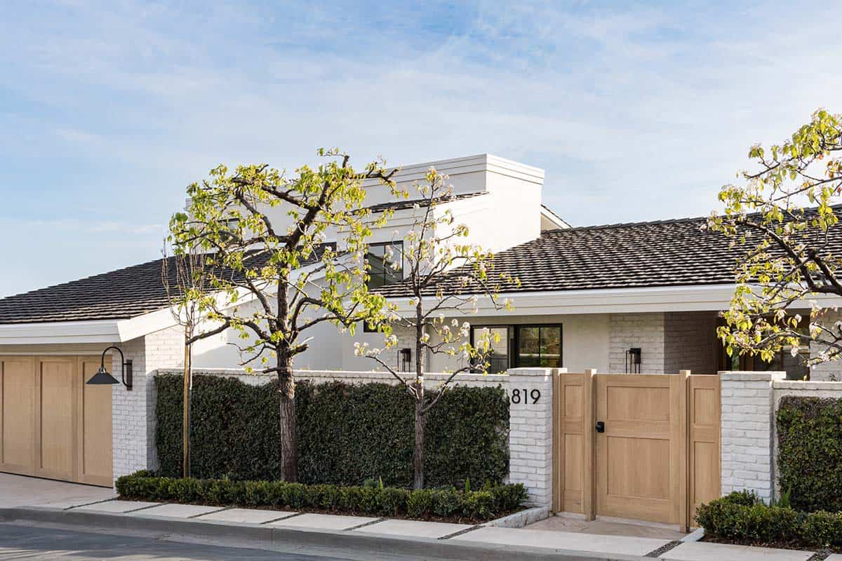 White stucco coastal home exterior with wood gate and hedge
