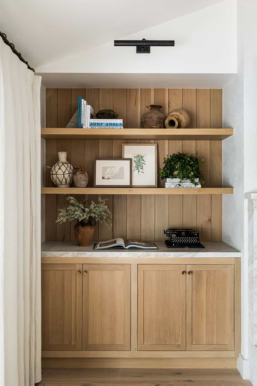 Built-in oak shelving with curated books and decorative pottery
