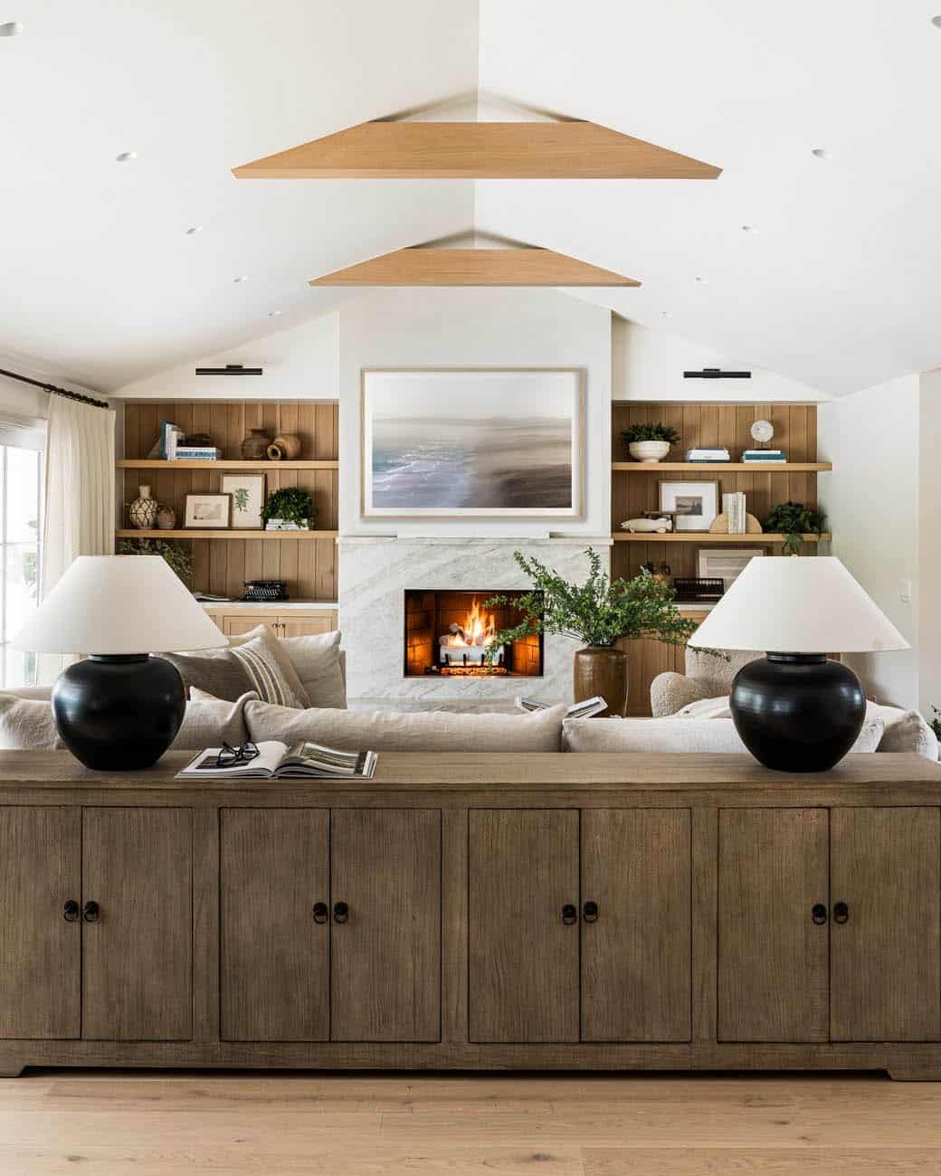 Living room fireplace flanked by wood shelving under angled beams