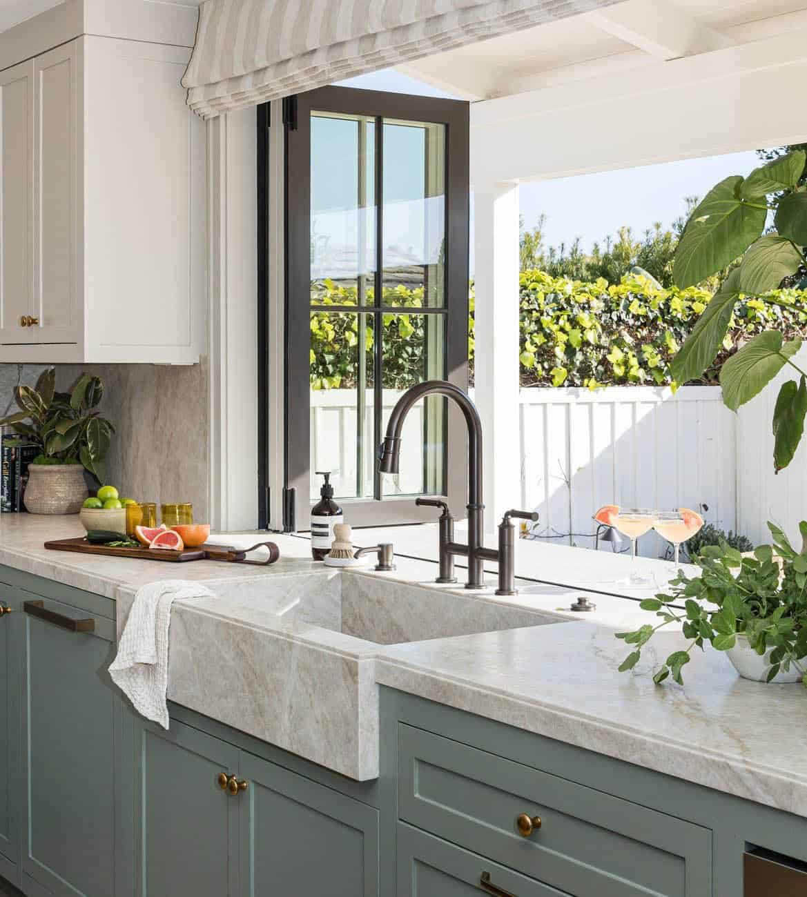 Kitchen pass-through window with marble sink and bronze bridge faucet