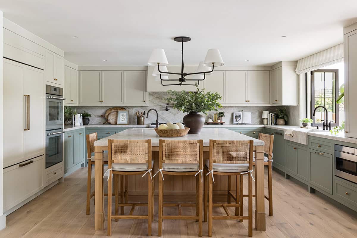 Kitchen island with sage cabinetry and woven counter stools
