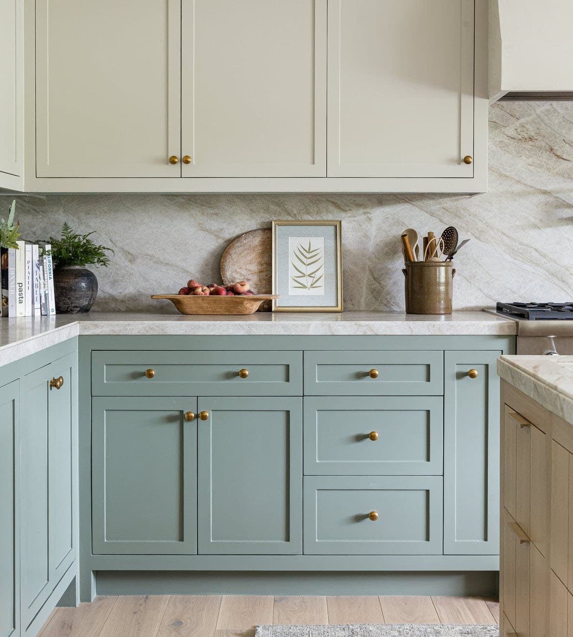 Sage green lower cabinets with brass hardware and marble backsplash