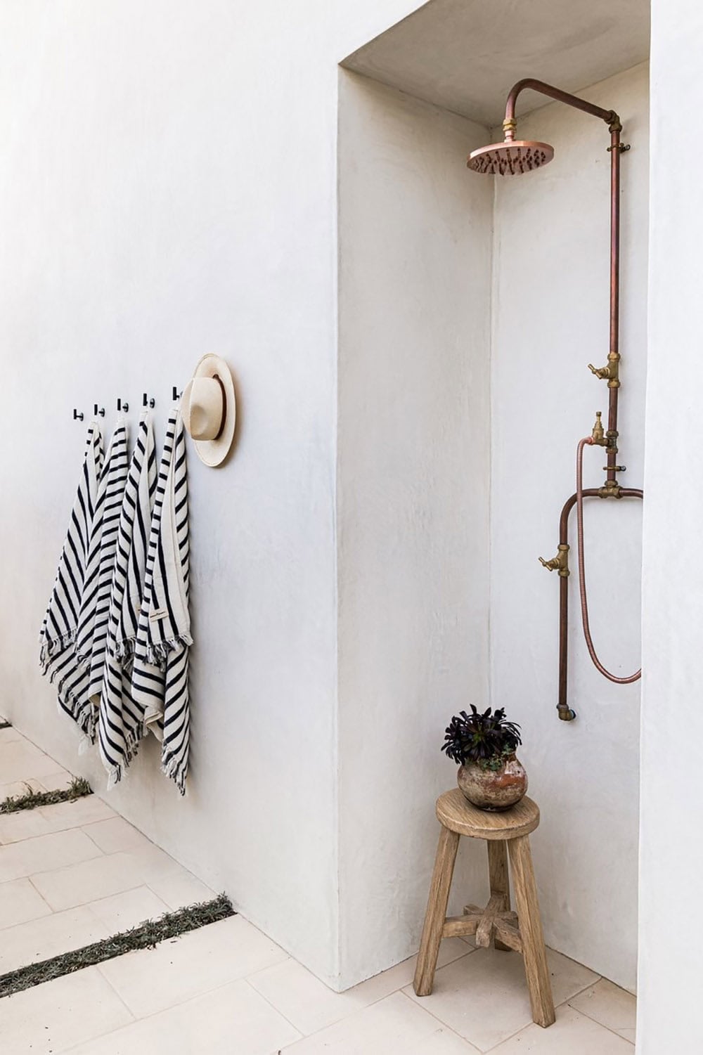 Outdoor shower nook with copper fixtures and striped towels