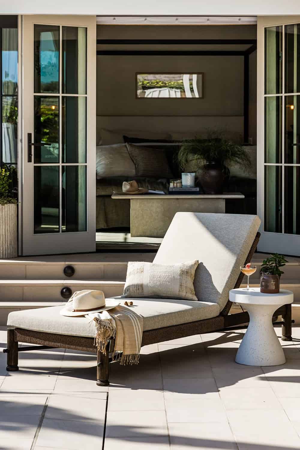 Poolside chaise lounge facing open French doors to bedroom