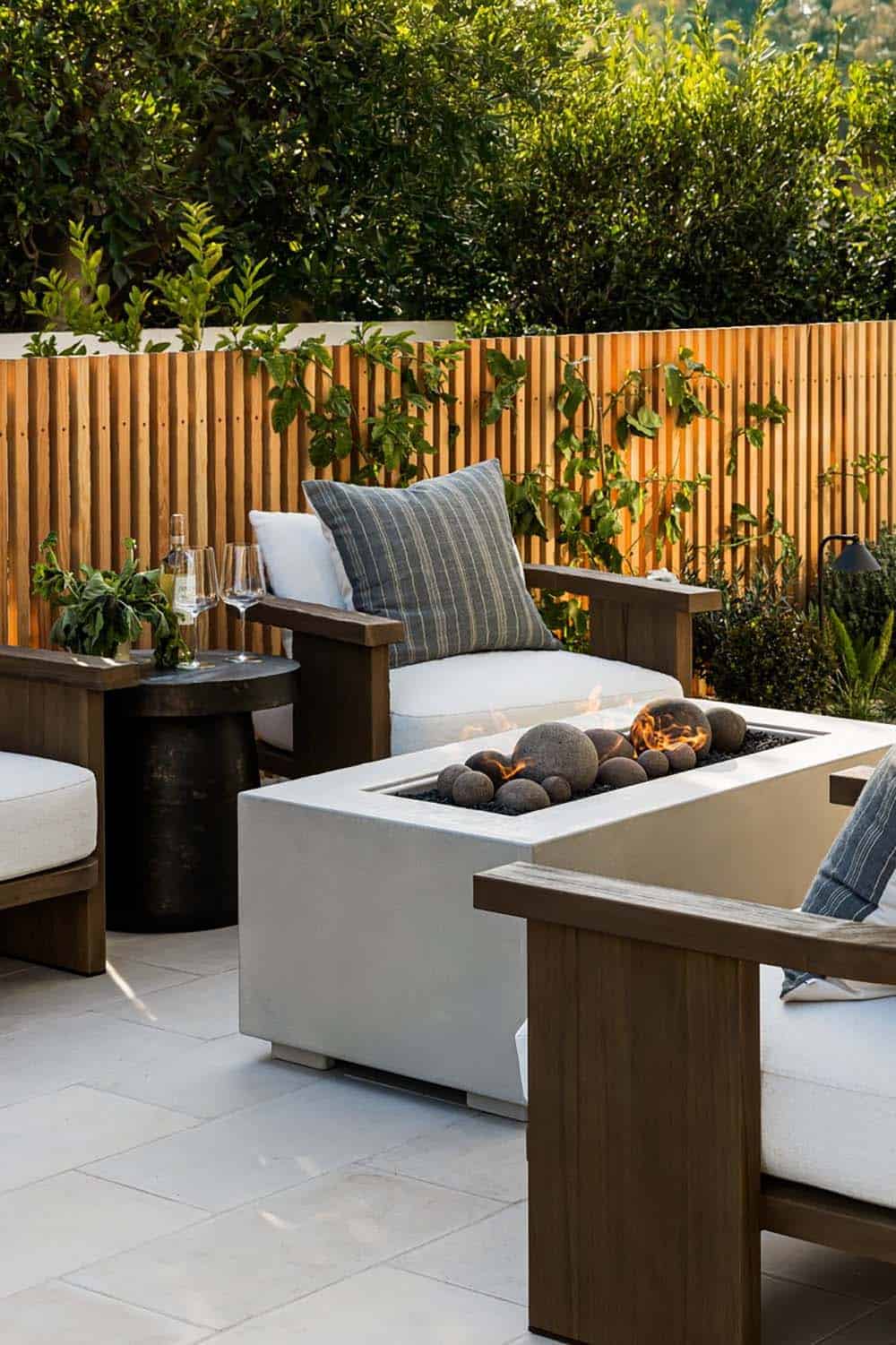 Outdoor fire pit table framed by teak lounge chairs